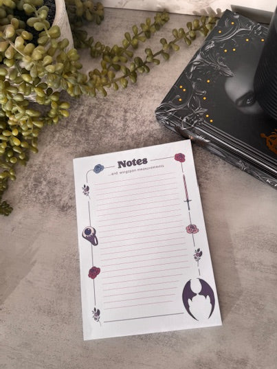 Lined notepad themed with ACOTAR wings, jurian eyeball ring, flowers, and a sword.